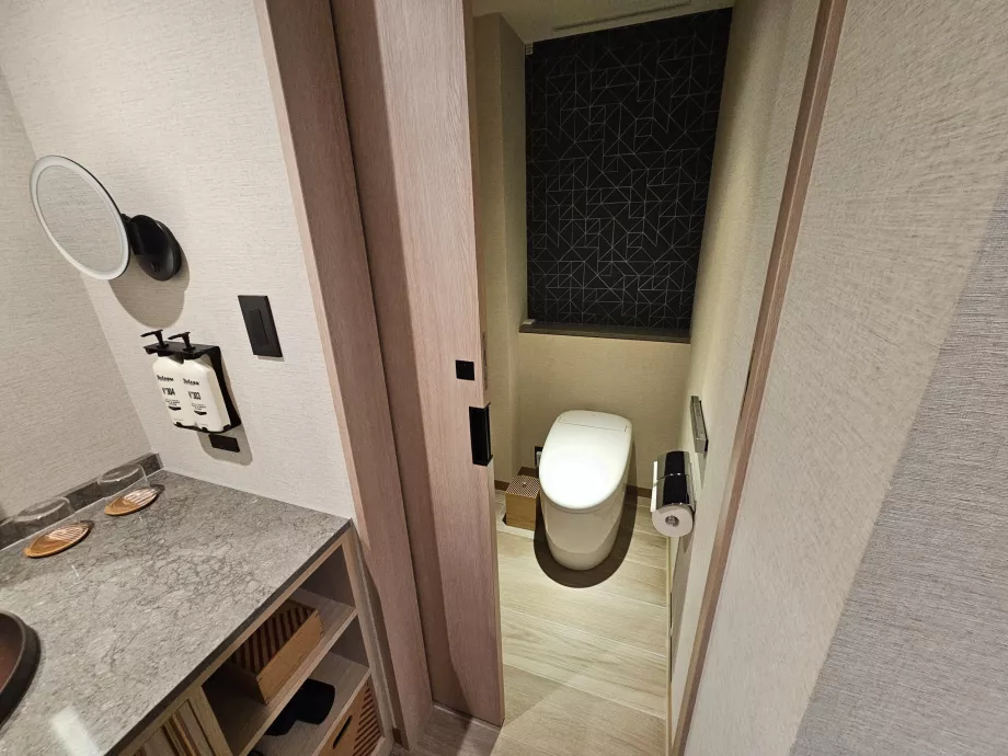 Toilet adskilt fra resten af badeværelset med en dør